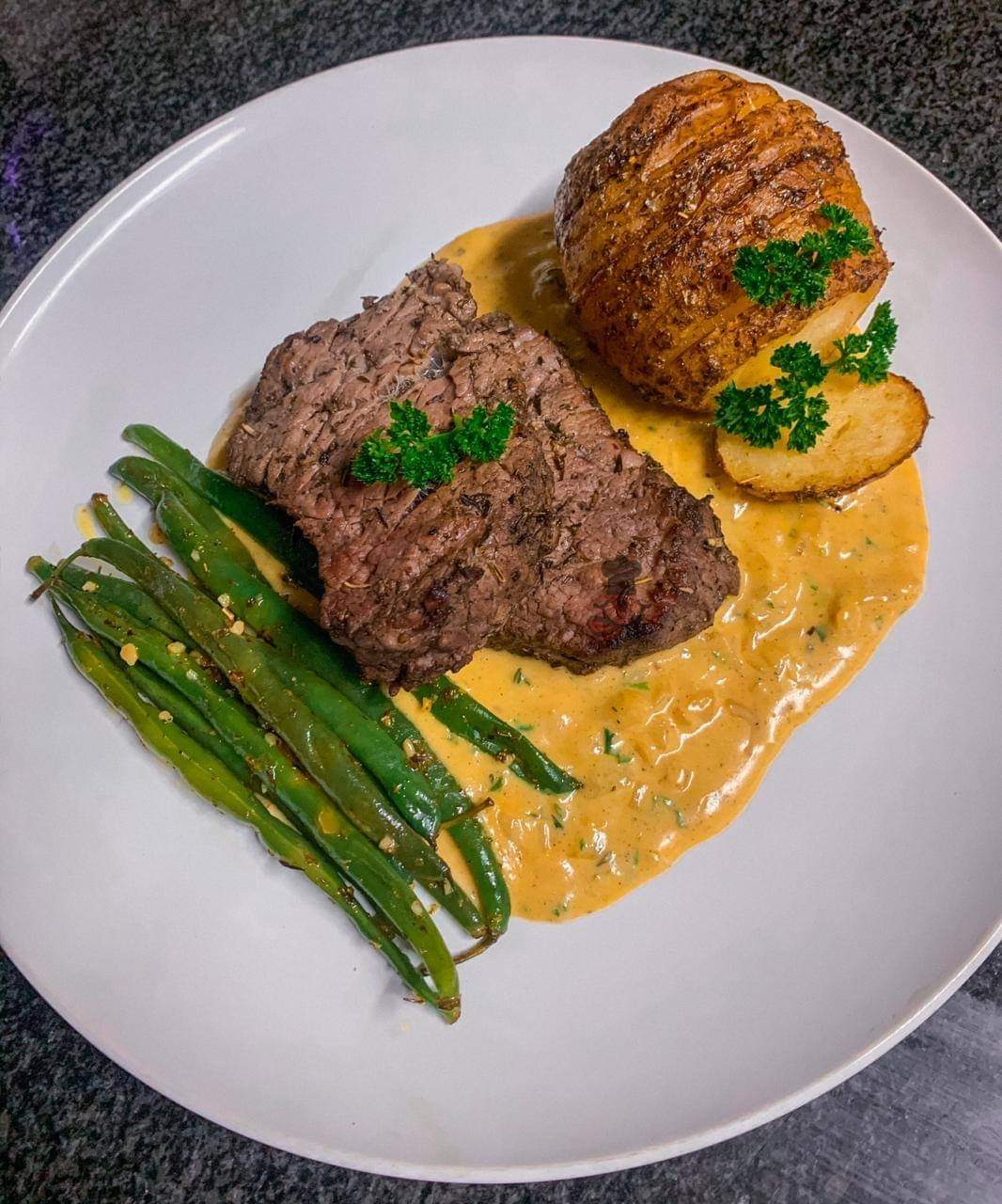 Beef fillet with a roasted potato side with green beans served with garlic sauce.